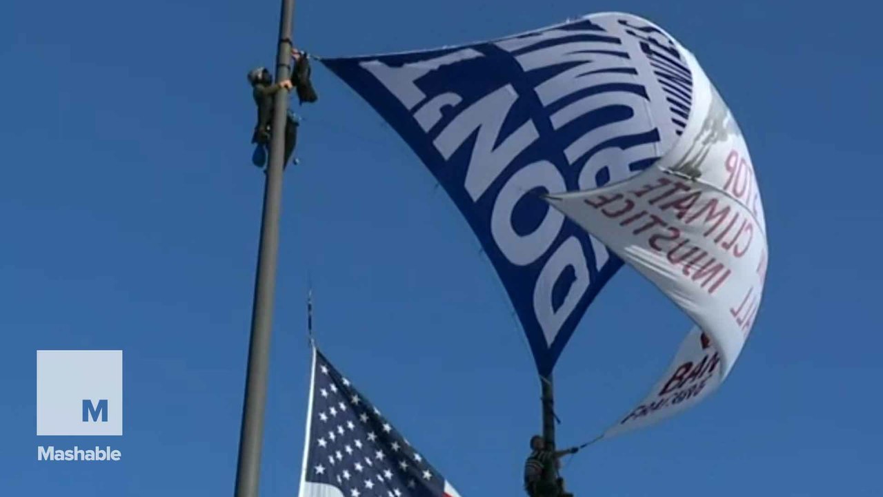 Title: Anti-Trump activists scale 60-foot flag poles outside Cleveland's Rock and Roll Hall of Fame