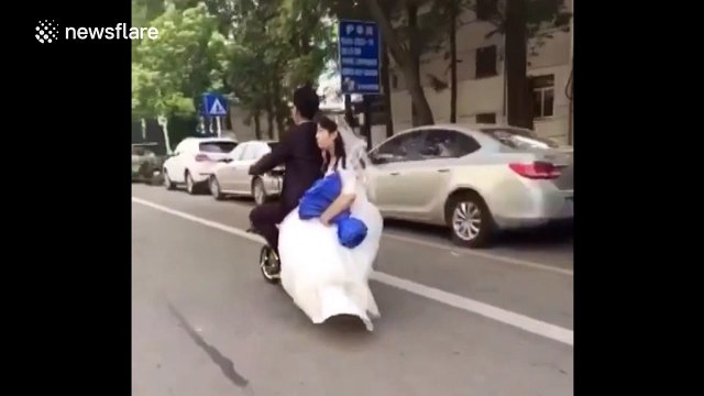 Groom doesn't notice his bride fall off the back of their wedding scooter