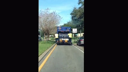 Bonne ambiance sur le camion poubelle - un rippeur danse à l'arrière
