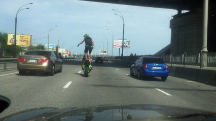 Man Rides Motorcycle Standing Up in Traffic