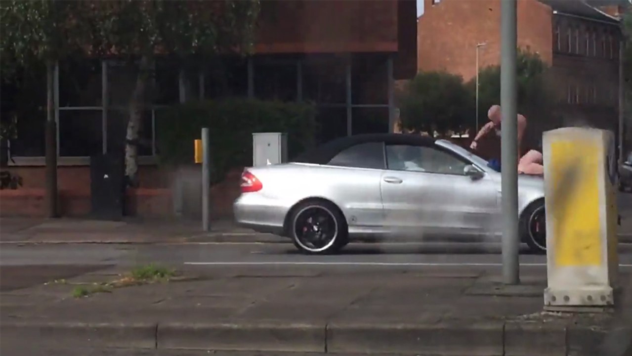 Ce mec tape sur le pare-brise d'une voiture avec ses poings