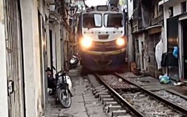 Train travels through narrow gap inbetween houses in Vietnam
