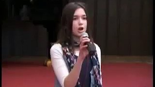 A young Dua Lipa singing at her school in Kosovo