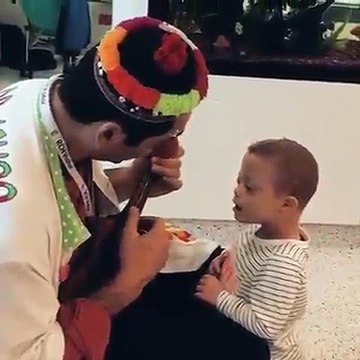 Homem com alguns acessórios na cara toca viola para ver criança com síndrome de down feliz