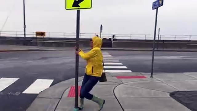 Woman Holds onto Street Sign during Hurricane Winds