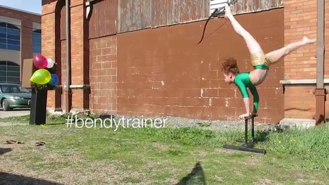 Girl shoots a bow and arrow with her feet while in a handstand