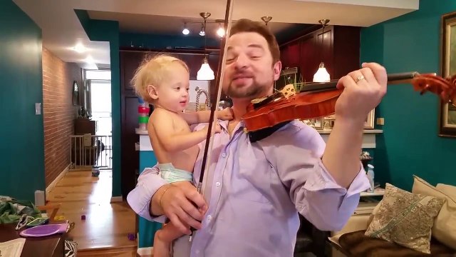 Un papa joue du violon avec son bébé dans les bras !