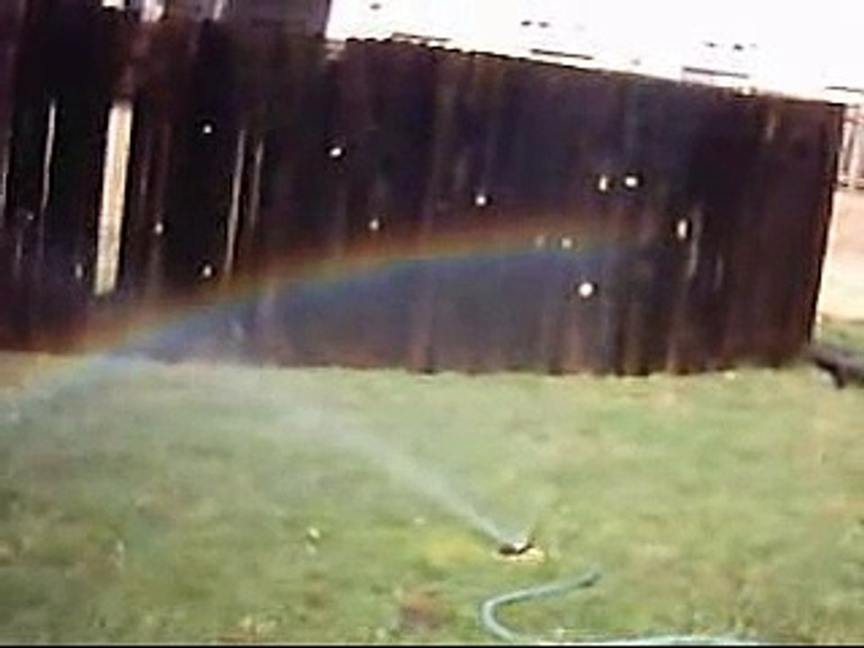 Cette femme râle contre un arc en ciel sur un arrosage automatique