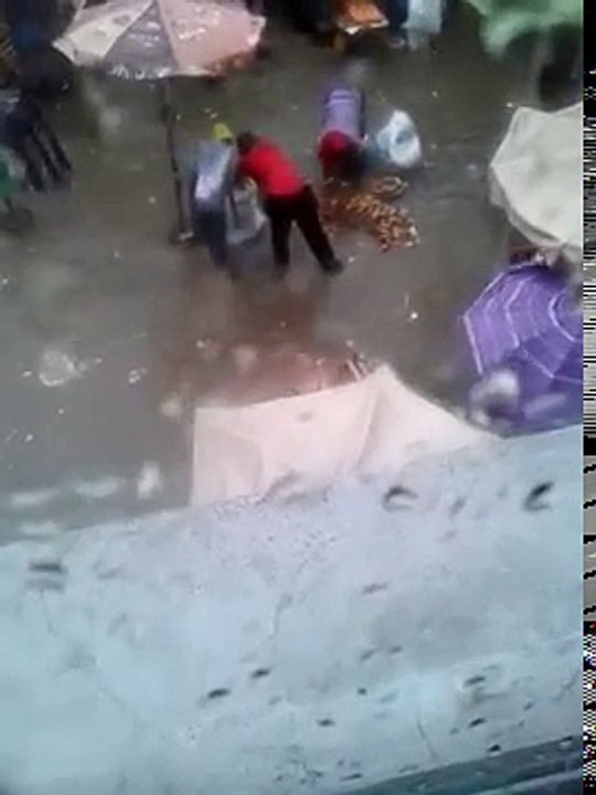 Des vendeurs lavent leurs légumes dans l'eau de la pluie au marché Castor
