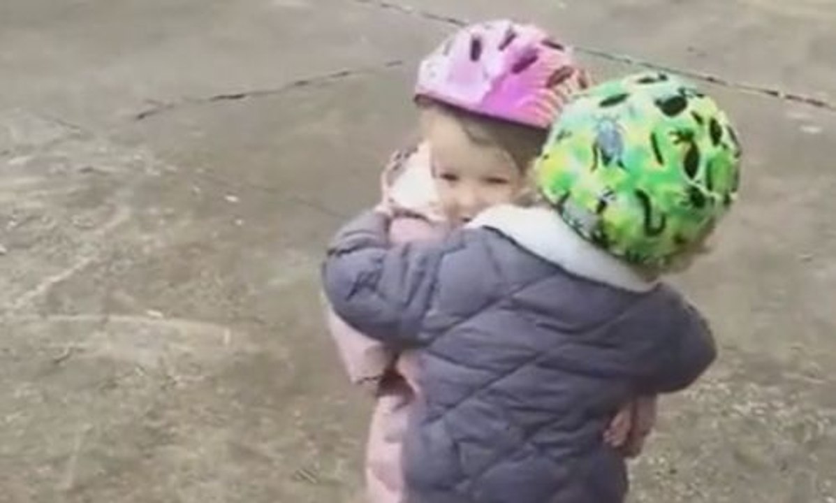 Une petite fille réconforte son copain qui vient de faire une chute à vélo.