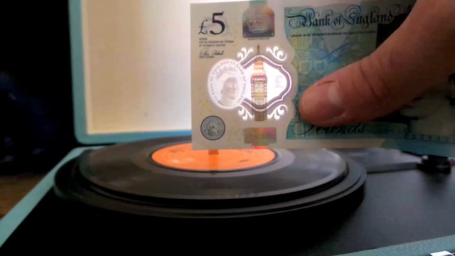 Le billet de 5 Livres anglaise fait de la musique sur une platine vinyle