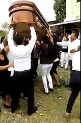 Un grupo de mujeres bailan con un ataúd en los hombros