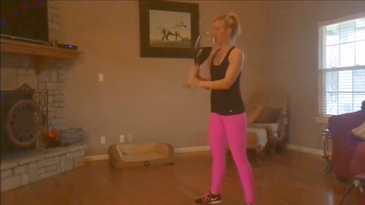 Cette fille prend une gorgée de vin après chaque squat