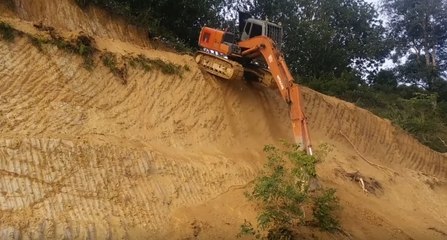 Un ouvrier prend de gros risques pour descendre une falaise en pelleteuse