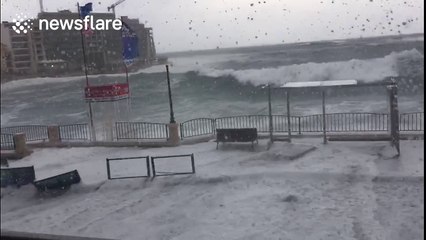 Massive waves crash against sea wall and spill onto promenade