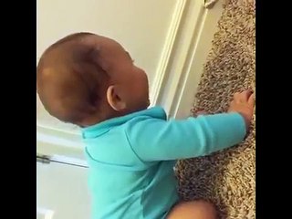 Cute baby laughs while playing with a spring door stop