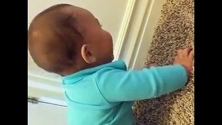 Cute baby laughs while playing with a spring door stop