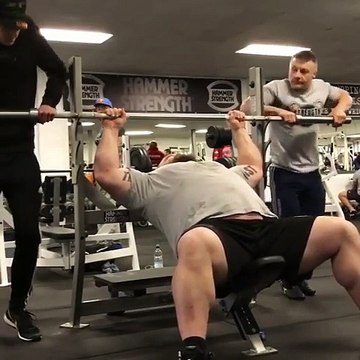 Un homme soulève une barre avec deux personnes dessus