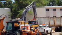 Deere 470G Excavator loading asphalt into a big rig dump truck some debris from a torn down building
