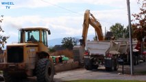 Deere Excavator loading a double dump truck while a Deere loader works nearby on a road construction