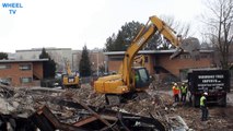 Deere excavator picking up building debris from a torn down building