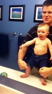 En face du miroir, papa joue des muscles, mais la réaction du bébé est à mourir de rire !