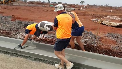 Travail d'équipe pour lisser une bordure en ciment