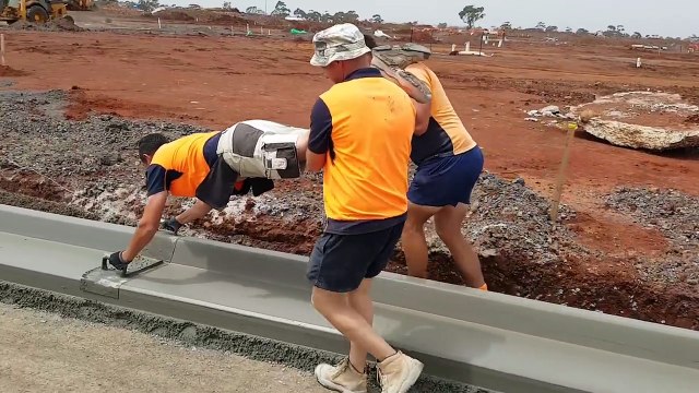 Travail d'équipe pour lisser une bordure en ciment