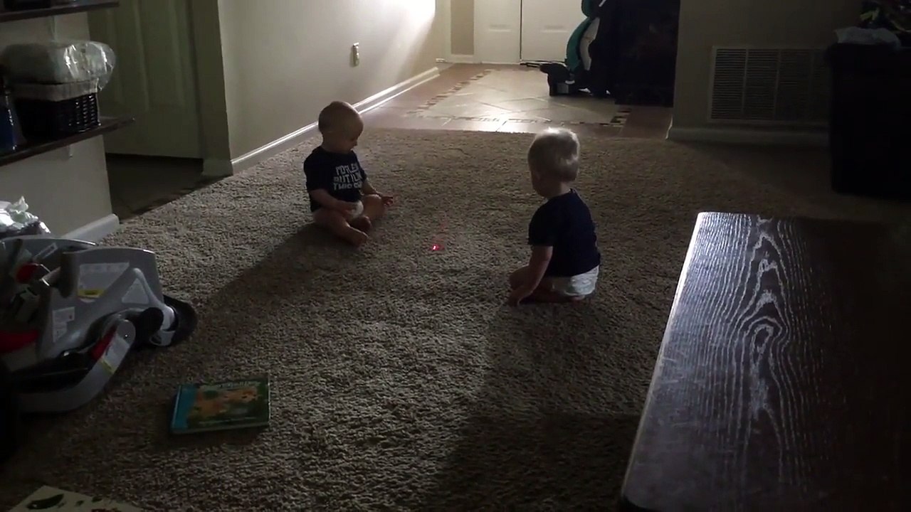 2 bébés jumeaux chassent un laser sur le tapis.. Trop mignon