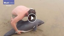 Man carries  dolphin back to the ocean