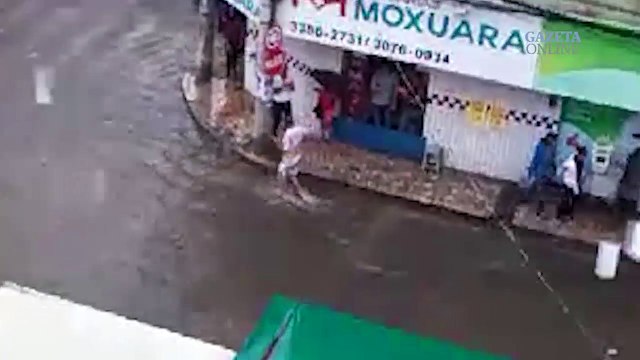 Pessoa nada no meio de rua alagada em Cariacica