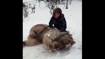 Elle fait un câlin à un gros nounours dans la neige, c'est adorable.