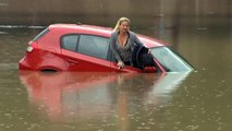 Une femme sur le toit de sa voiture dans une inondation