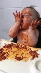 Un bébé fatigué mange des pâtes à la bolognaise