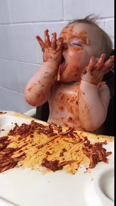Un bébé très fatigué mange des pâtes à la bolognaise