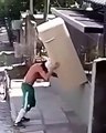Güçlü adam bisikletle buzdolabı taşır.