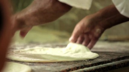 Neapel.Pizzabäcker-Teig mit der Hand dehnen