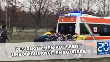 Des rugbymen poussent une ambulance embourbée à côté d'un terrain
