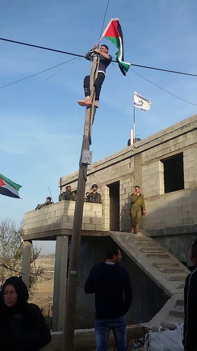 فلسطينيون يتحدون جنود الاحتلال برفع علم بلادهم أمام العلم الإسرائيلى