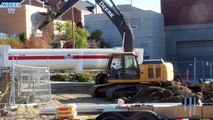 Deere 200D excavator loading asphalt and dirt into a 20 ton big rig dump truck on a construction site