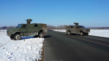 Un F-16 se gare à côté de deux véhicules militaires Dingo