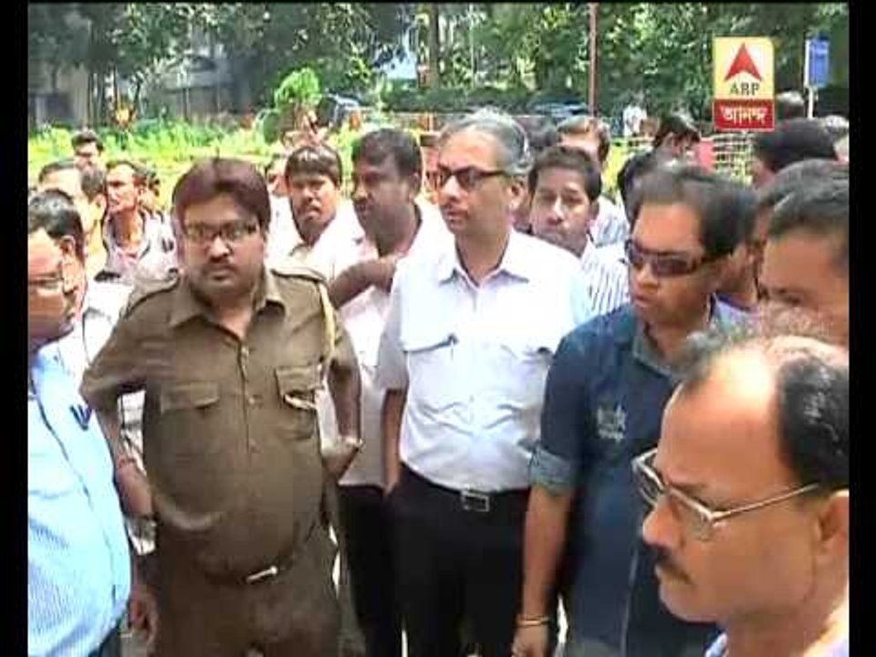 JU VC entering campus, cordoned by securitymen, while students shout slogans.