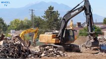 Deere 270D Excavator moves rubble and debris from a torn down building while a CAT Excavator works