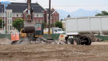 Deere 270D Excavator loading huge chunks of cement into a big rig dump truck