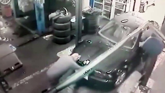 Un mécanicien tombe dans un trou en poussant une voiture