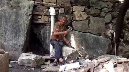 2017 Old man in china building a stone house in mountains.