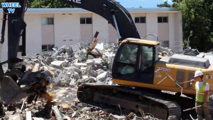 Deere 270D Excavator moving lots of debris from torn down dorm buildings on a college campus