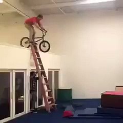 Un jeune tente sauter sur un matelas en vélo en étant sur une échelle