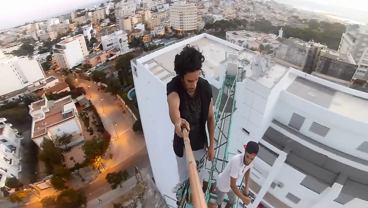 Deux abrutis font des tractions en haut d'une grue.