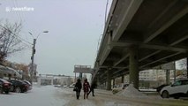 Snow cascades over bridge, narrowly missing pedestrians